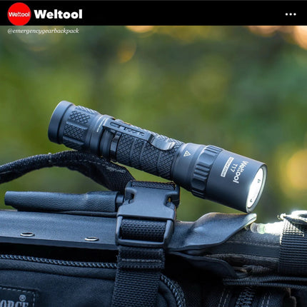 Weltool T17 flashlight on a backpack with Weltool branding against a blurred green background