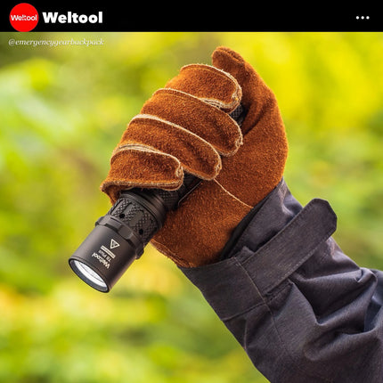 Weltool T8Plus  flashlight held by a person against a blurred green background, featuring Weltool branding.